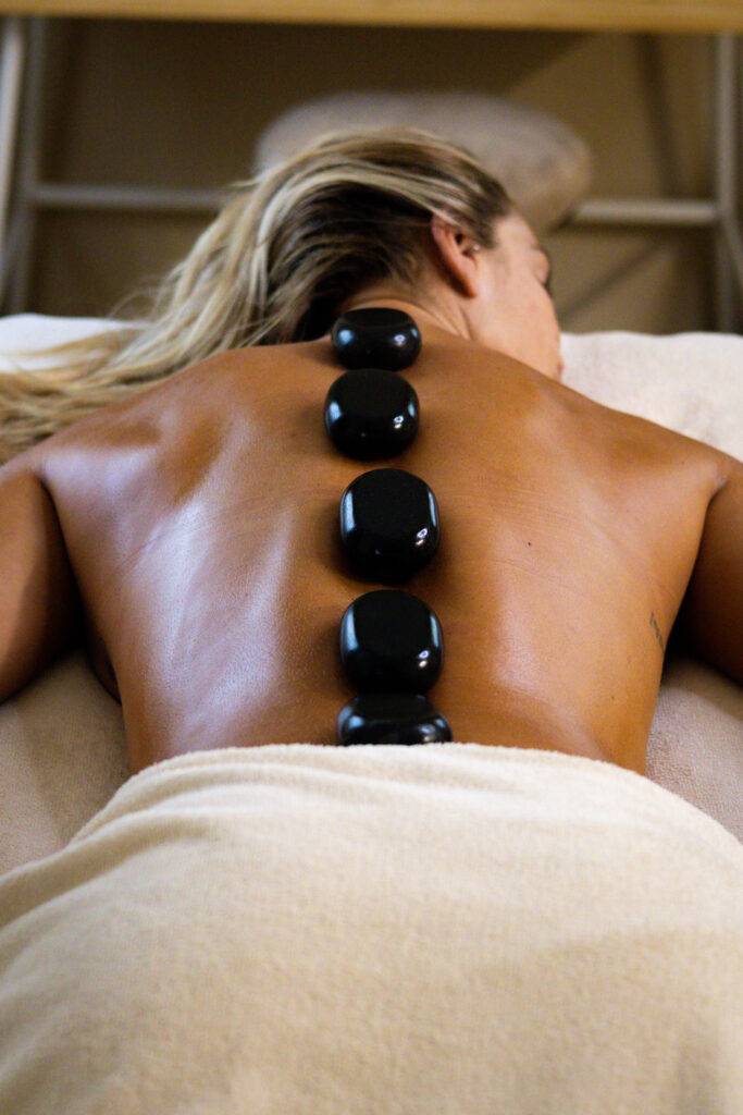 Mélanie, praticienne du Spa de Mélanie à Nîmes, effectue un massage aux pierres chaudes avec des manœuvres enveloppantes et relaxantes.